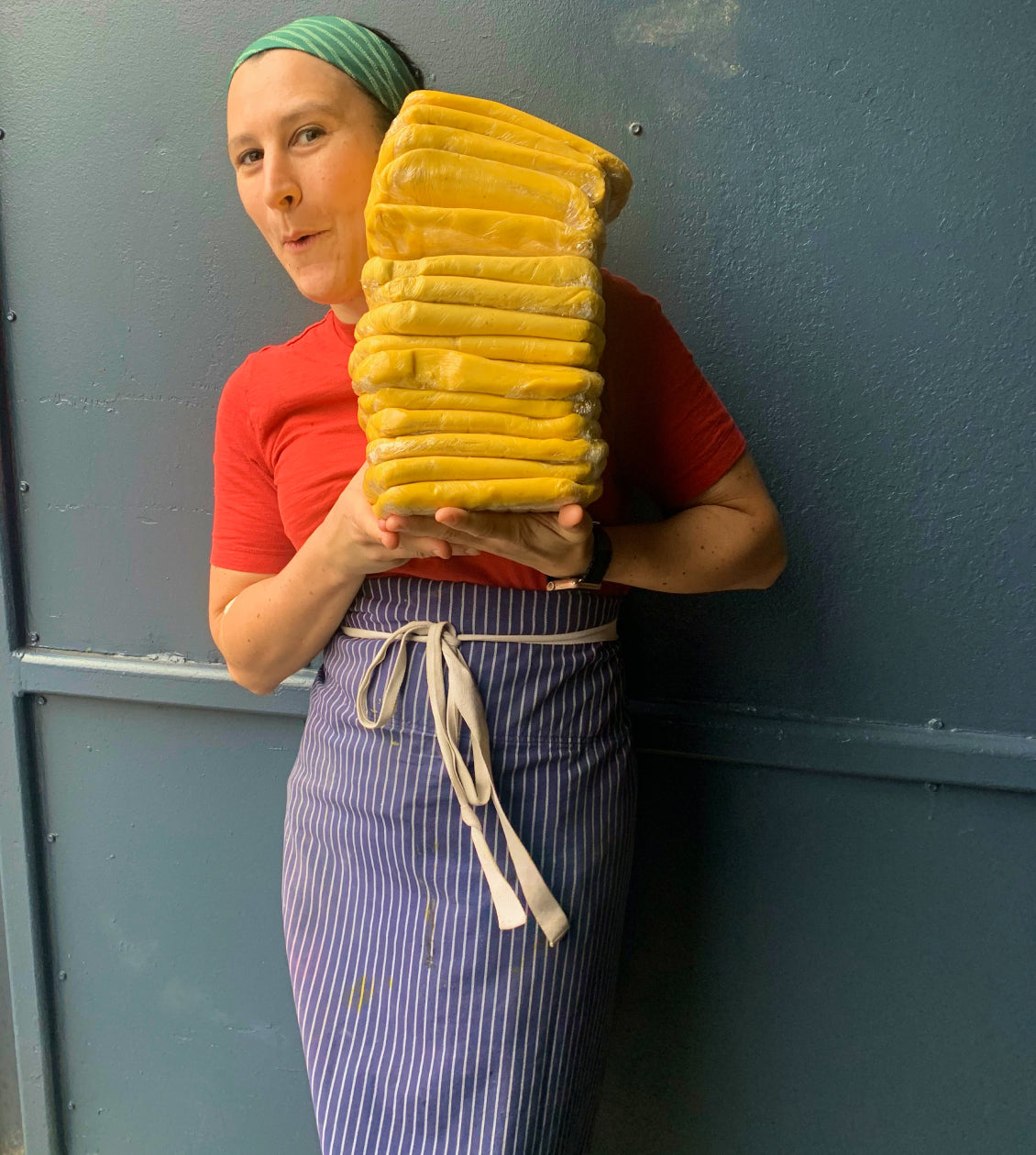 Laurie Ellen portant une pile de pâtons avec un grand sourire.