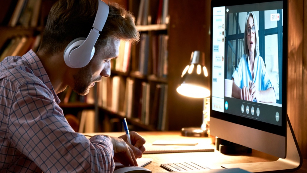 A person taking note while watching a live stream on his PC.