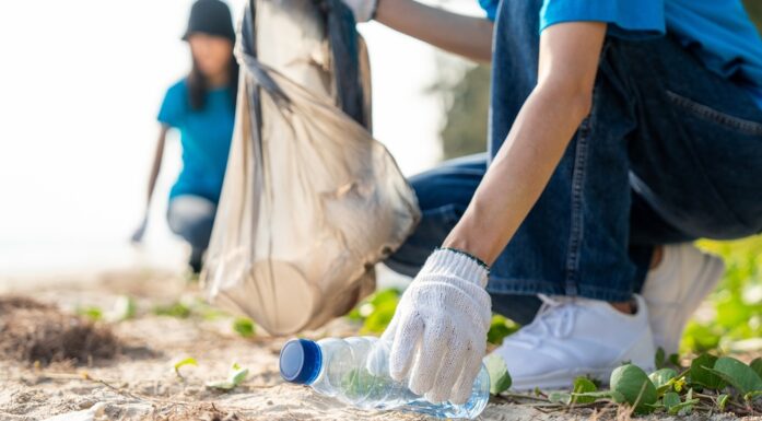Plast. Bildet viser folk som plukker plast fra en strand.
