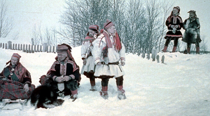 Foto av en gruppe samer i festdrakt ute i snøen.