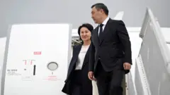 Садир Жапаров рафиқаси Айгул Жапарова билан самолётдан тушиб бормоқда.