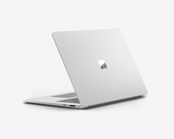 Surface Laptop i fargen platina delvis åpen, satt mot en lys bakgrunn.