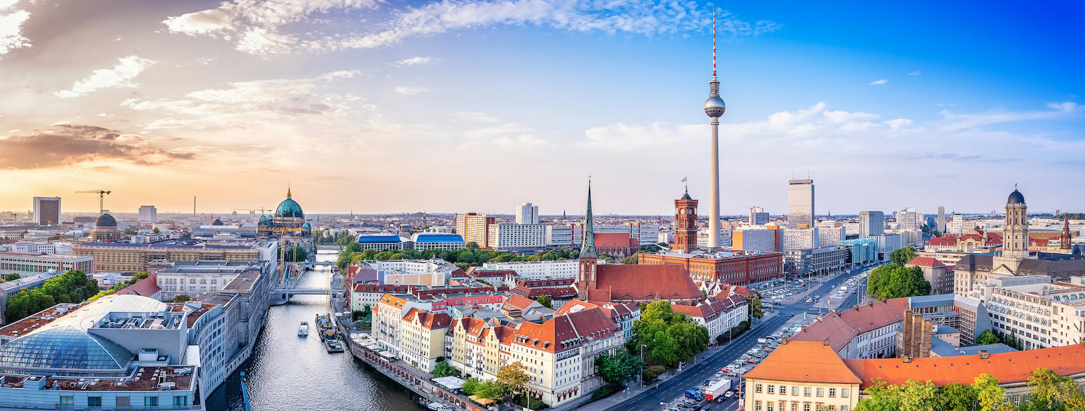 Utsikt over en stor by med en elv. Litt til høyre i bildet er et langt tynt tårn med en kule høyt opp, og en rød og hvitstripet lang, tynn tupp. Foto