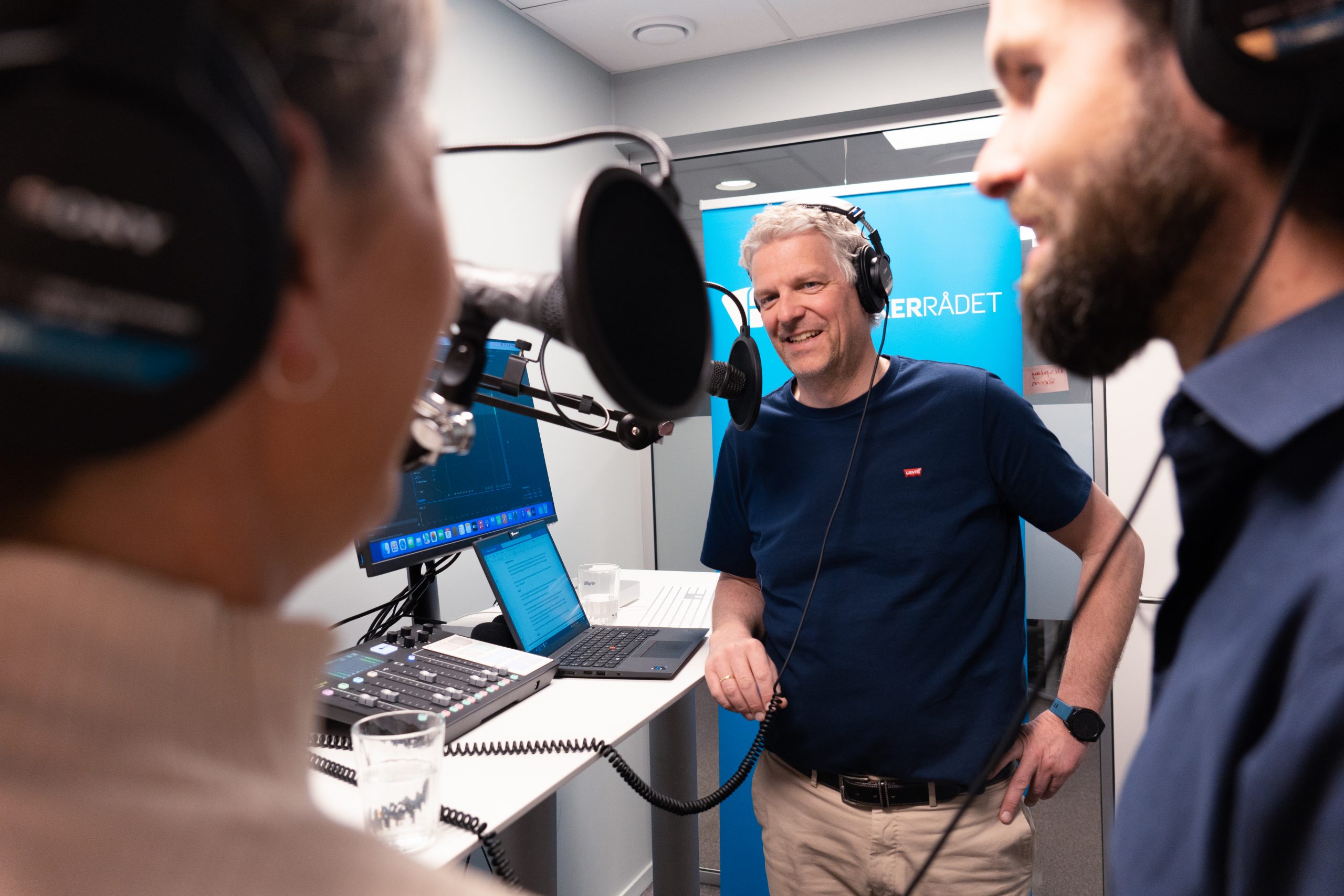 Bilde av programleder i studio med mikrofoner.Foto