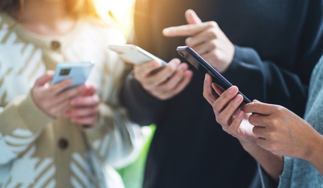 Hender som taster på mobil.Foto