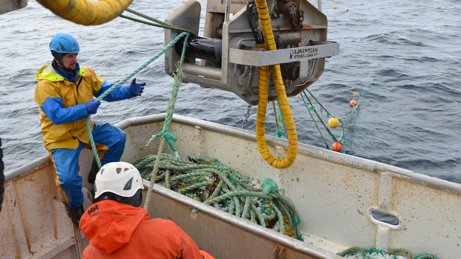 Fiskere på fiskebåt heiser opp fiskenot