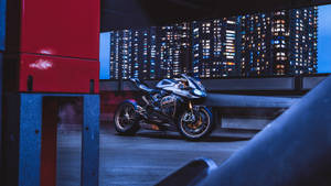 Sleek silver Ducati motorcycle parked on rooftop with glowing city skyline behind. — Ducati Wallpaper