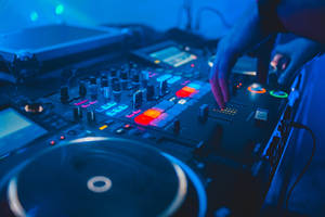 DJ hand adjusting glowing controls on a music mixer under blue lights. — Dj Wallpaper