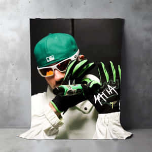 Man in green cap and white sunglasses holding spray can wearing black and green gloves with 'MATHA' on them. — Feid Wallpaper