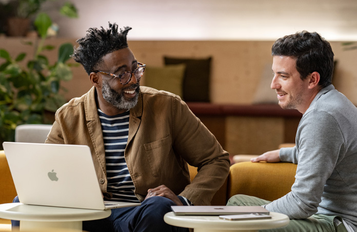 En åpen MacBook på et bord foran en smilende person