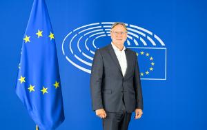 photo of MEP Bernd Lange, INTA Chair, standing next to the flag of EU; blue background with the EP logo.
