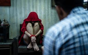Woman sitting with a hoodie and hands cuffed