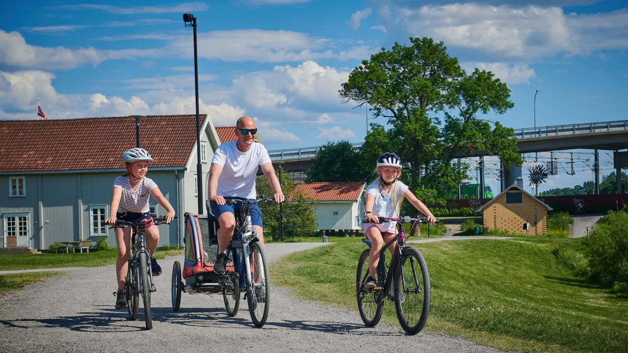 En mann som sykler med to barn.