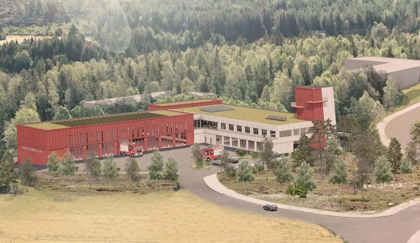 En stor rød bygning i skogen med solceller på taket.