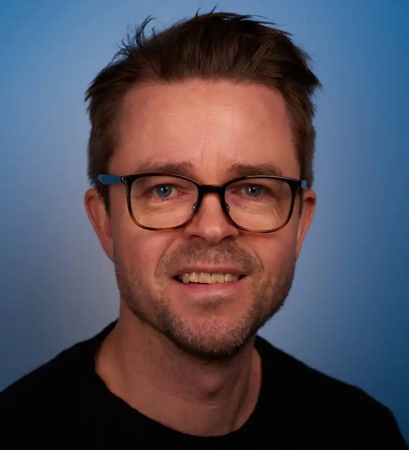 En mann med briller og svart skjorte.