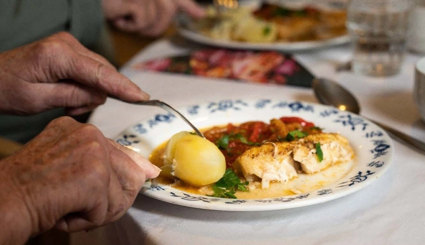 En person som skjærer mat på en tallerken.