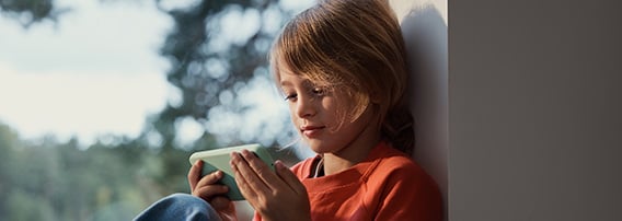 Barn slapper av med mobilen i vinduskarmen