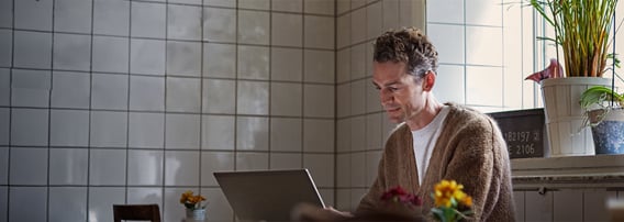 Fornøyd mann sitter med laptop på en kafe