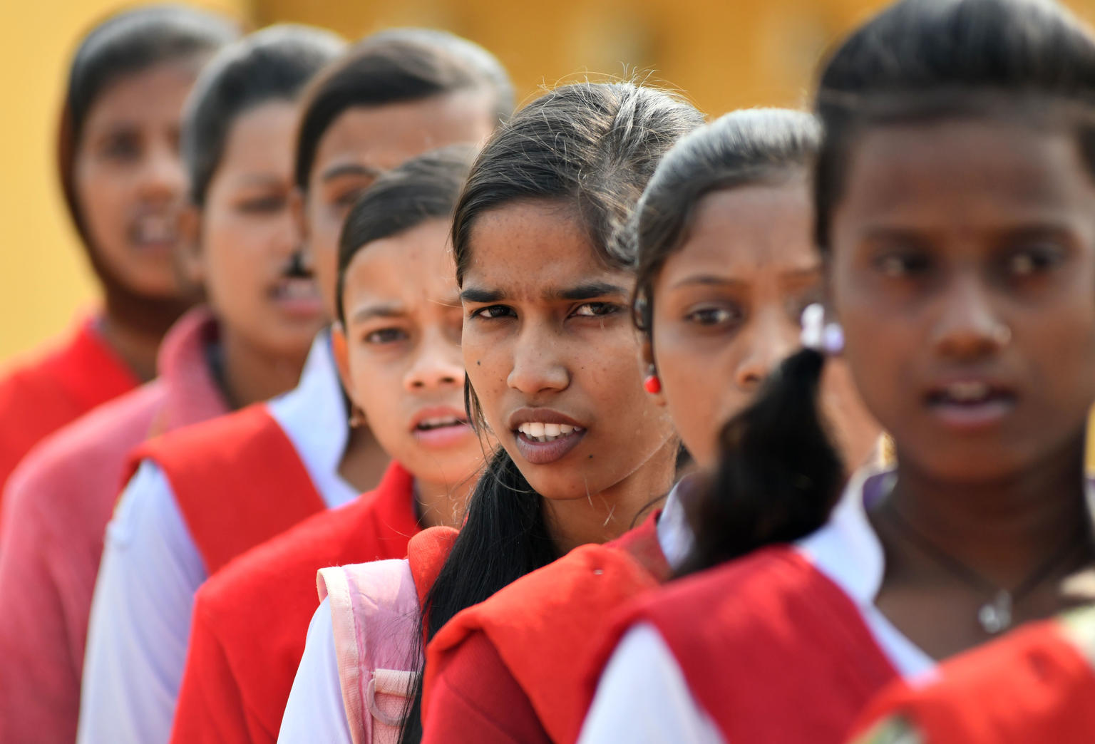 Grupo de niñas jóvenes en la escuela con un uniforme rojo en una fila 