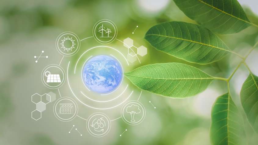 Green leaves and an image of blue globe surrounded by green technology symbols like solar energy or wind energy